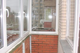 Вид изнутри кирпичной кладки на перилах остекленного балкона