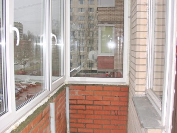 Вид изнутри кирпичной кладки на перилах остекленного балкона